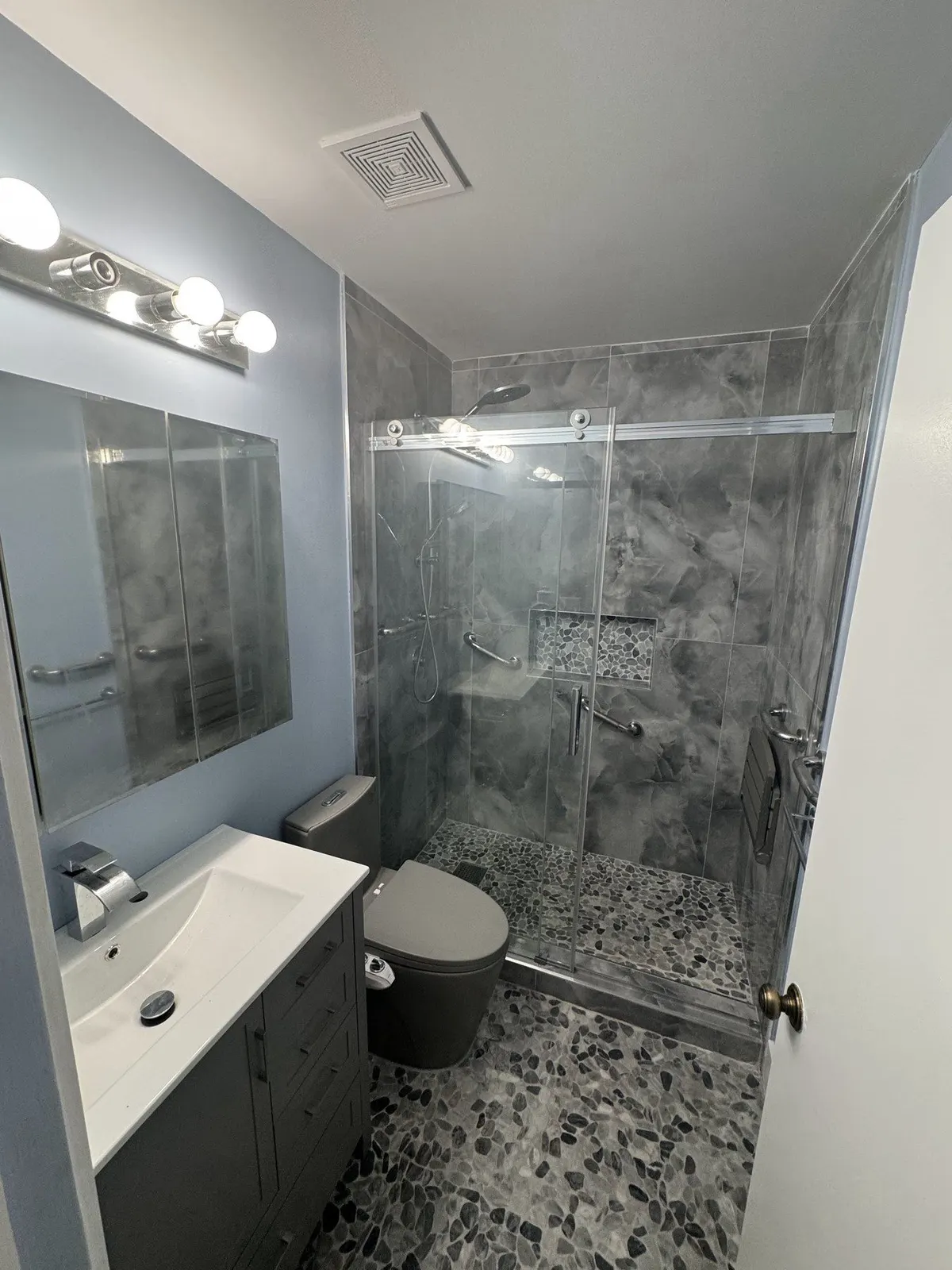 Modern bathroom with glass-enclosed shower and marble-look wall tile.