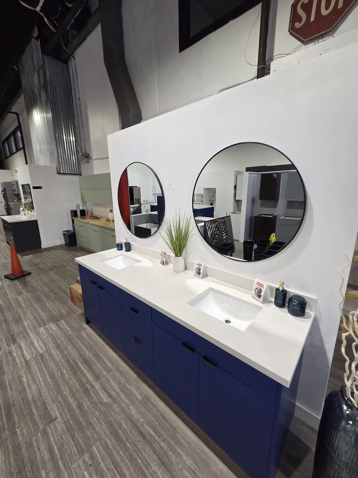 Double-sink white countertop with navy vanity and two round mirrors in showroom.